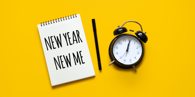 a notepad that says NEW YEAR NEW ME with an alarm clock and pen