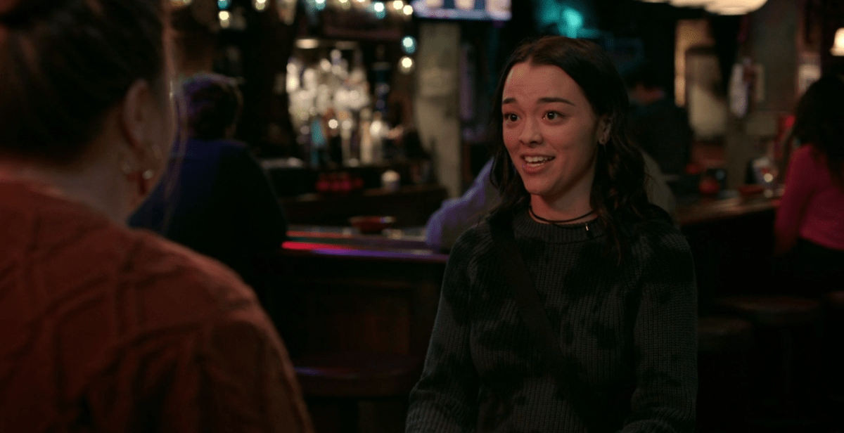 Best queer TV scenes of 2023: a young woman talks to another woman sitting across from her at bar with an anxious smile on her face.