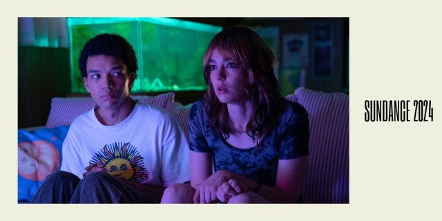 I Saw the TV Glow: A still of Justice Smith sitting on a couch next to Brigette Lundy-Paine. A beige background with Sundance 2024 on the side.