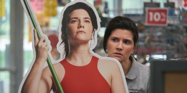 Elise Bauman One More Time: Elise as Jen Hauser glares at a cardboard cutout of herself holding a javelin