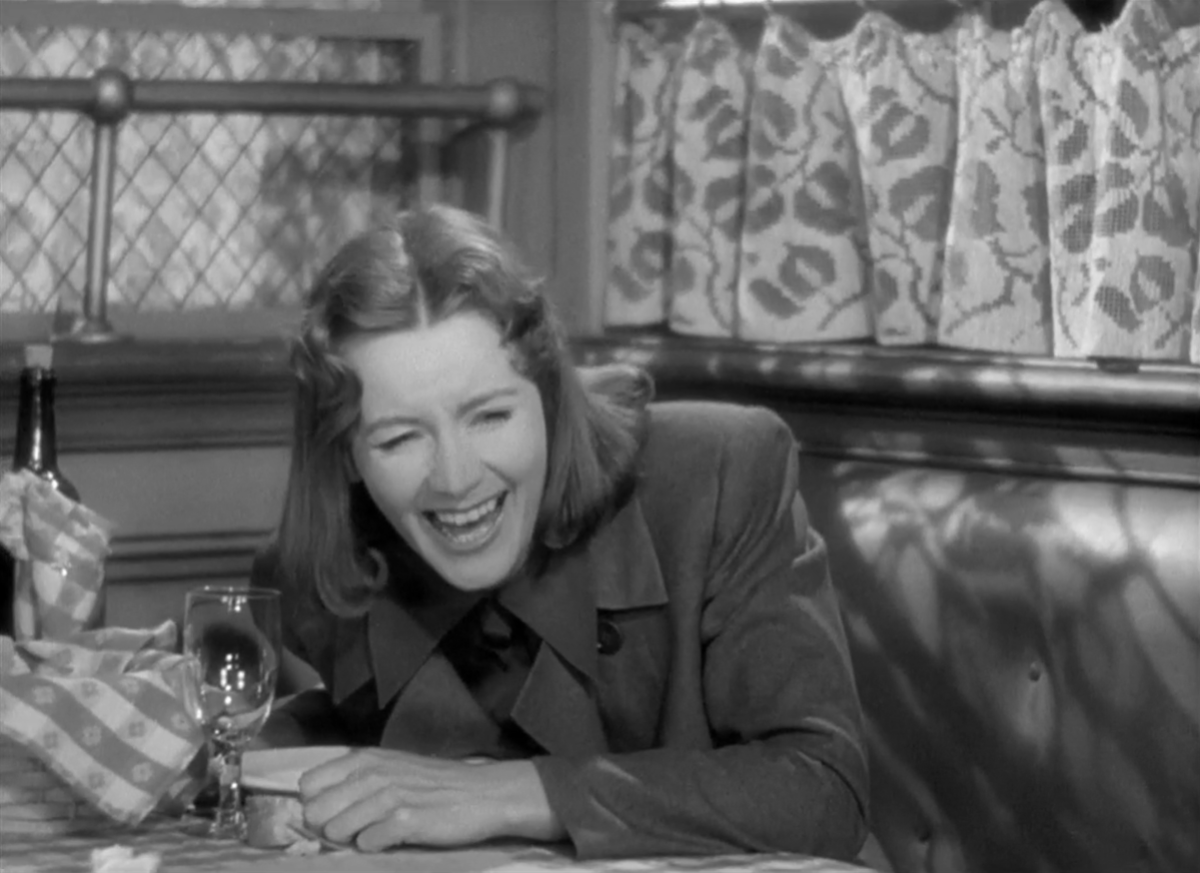 Greta Garbo laughing at a table