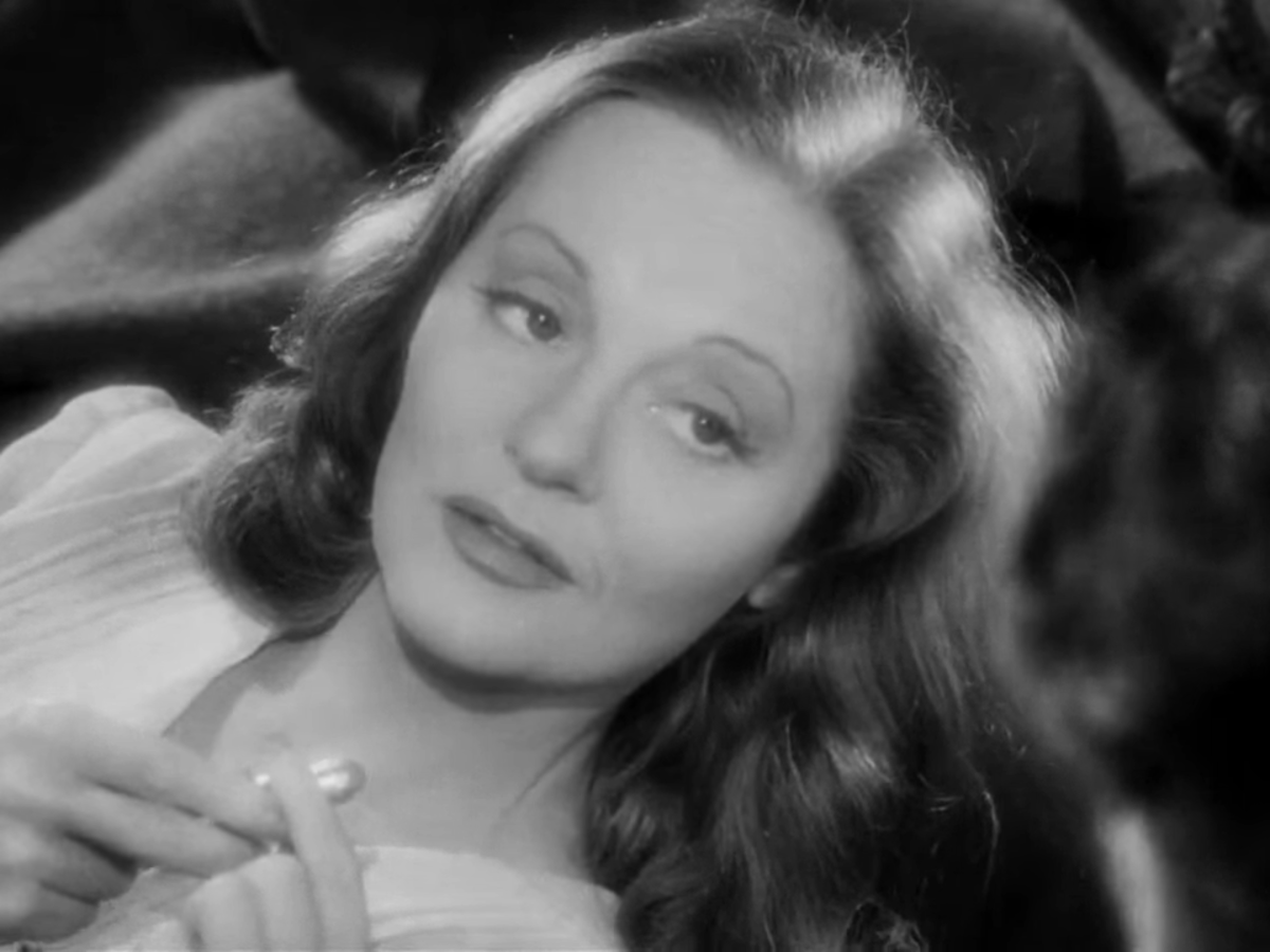 Close up of Tallulah Bankhead as she holds lipstick.