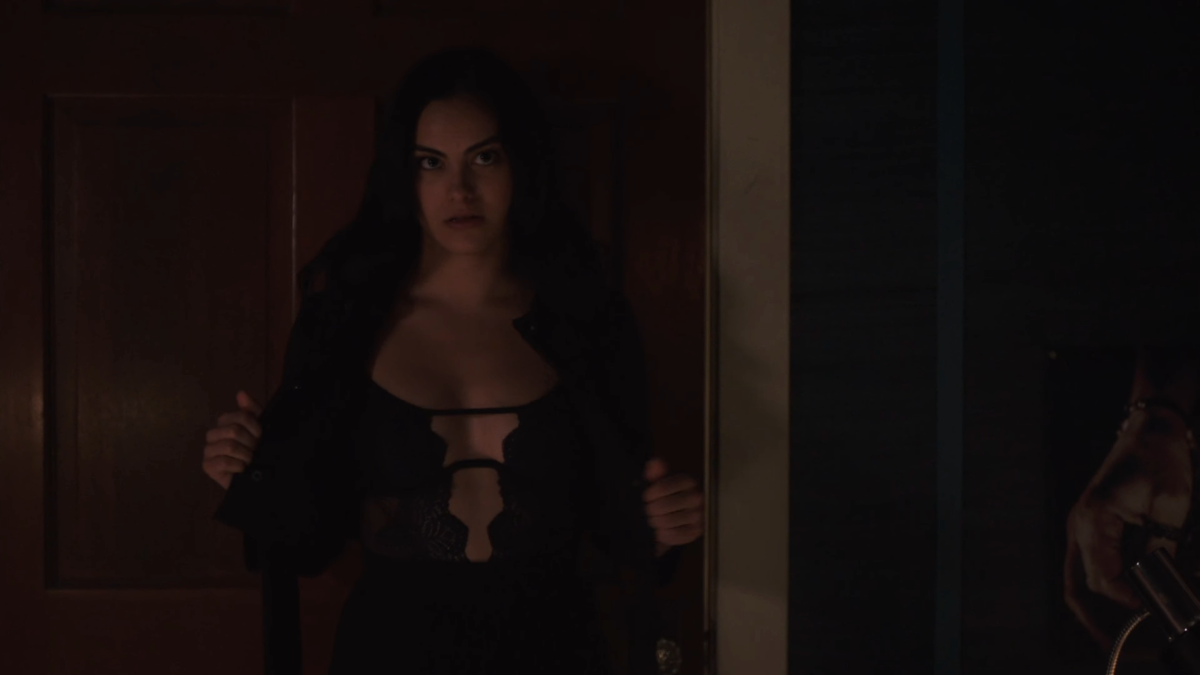Veronica takes off her coat revealing cleavage.