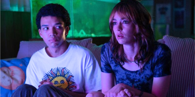Justice Smith sits on a couch next to Brigette Lundy Paine in I Saw the TV Glow
