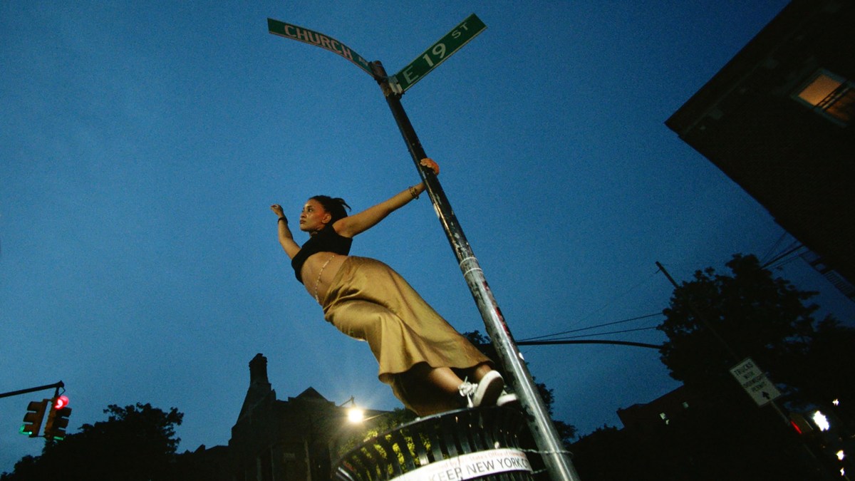 Sundance 2024 queer: A still from Tendaberry of Kota Johan holding onto a street sign with one arm.