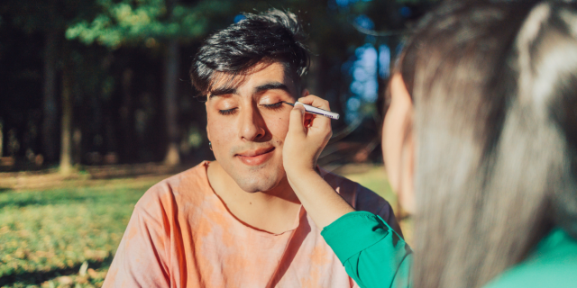 a friend applying makeup to a transfemme person, demonstrating a way to support transitioning partner or friend