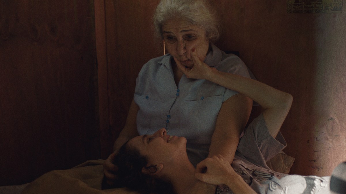 A still from Malu by Pedro Freire: Carol Duarte lies in Juliana Carneiro Da Cunha's lap and squeezes her face.