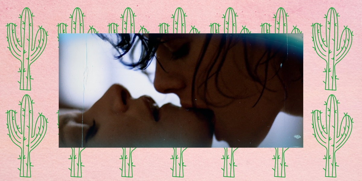 An image of Cay kissing Vivian's chin from the Desert Hearts sex scene against a pink backdrop with green cactus drawings