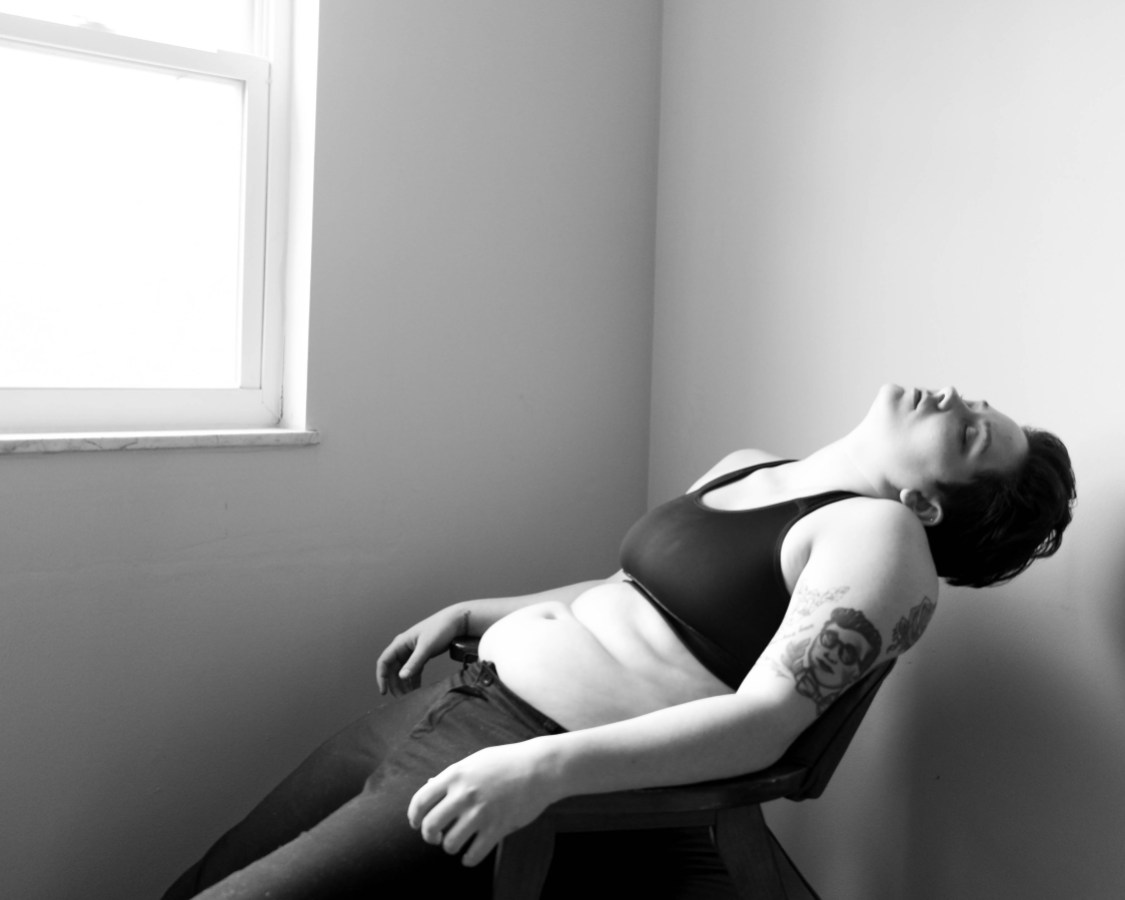 Julie Rae Powers in repose in black and white, wearing black sports bra and black jeans