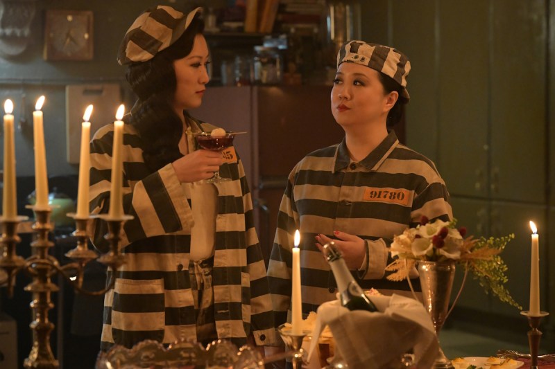 Alice and Sumi arrive at Kelly's candle-filled murder mystery party dressed as escaped prisoners.