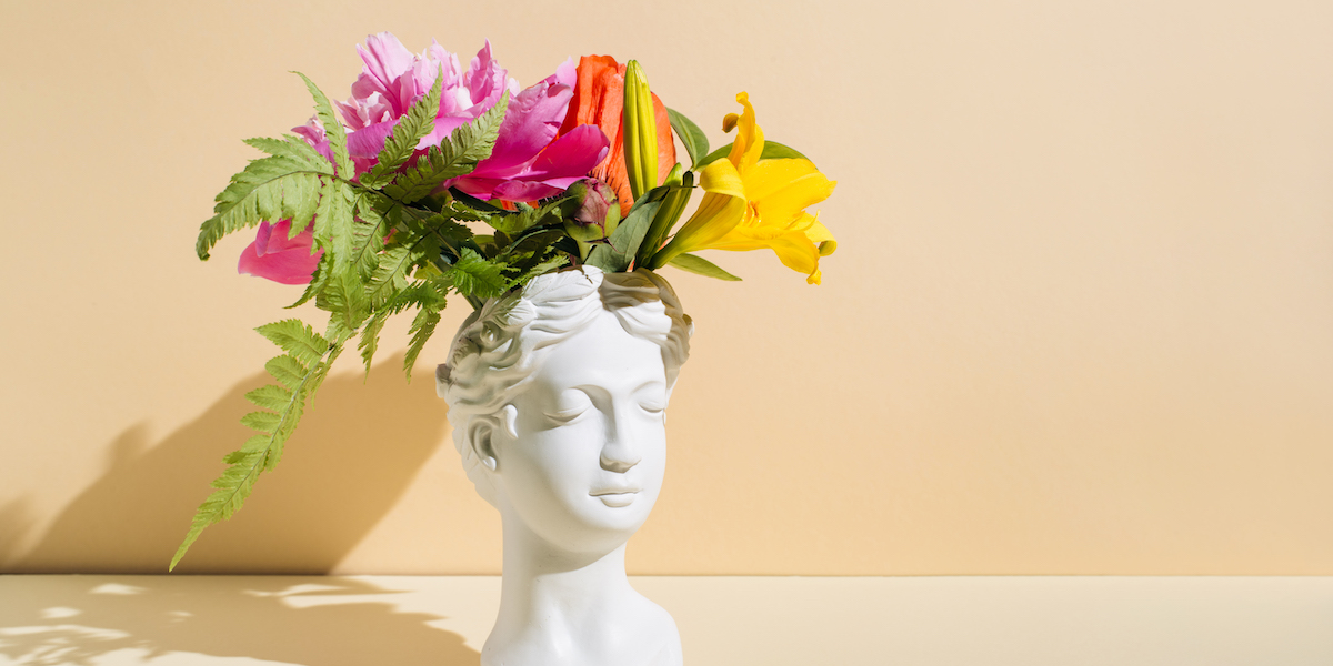 Retro head sculpture with flowers on beige background. Creative positive thinking concept. Minimal Mental Health Awareness Month. Psychology, emotional wellness, progress, flowering, Work on yourself idea
