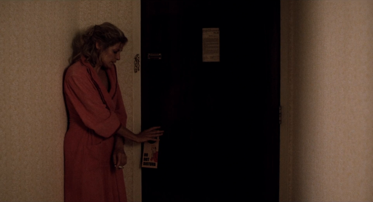 Vivian cowers in the corner holding her hotel door shut.