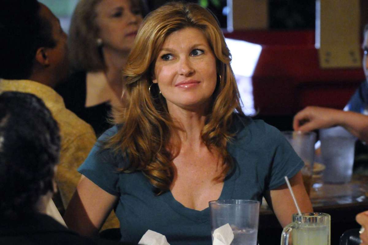 Connie Britton as Tami Taylor sits at a table and looks off to the side.