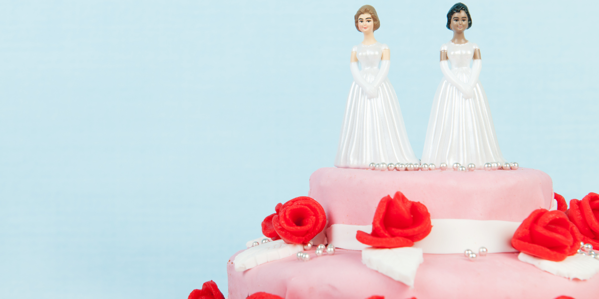 a wedding cake with two bride toppers