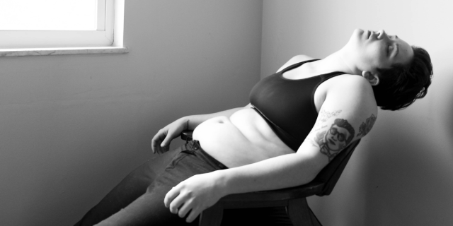 Julie Rae Powers in repose in black and white, wearing black sports bra and black jeans