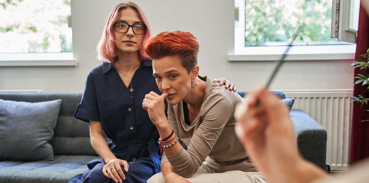 Supportive woman touching shoulder of her wife during psychotherapy session