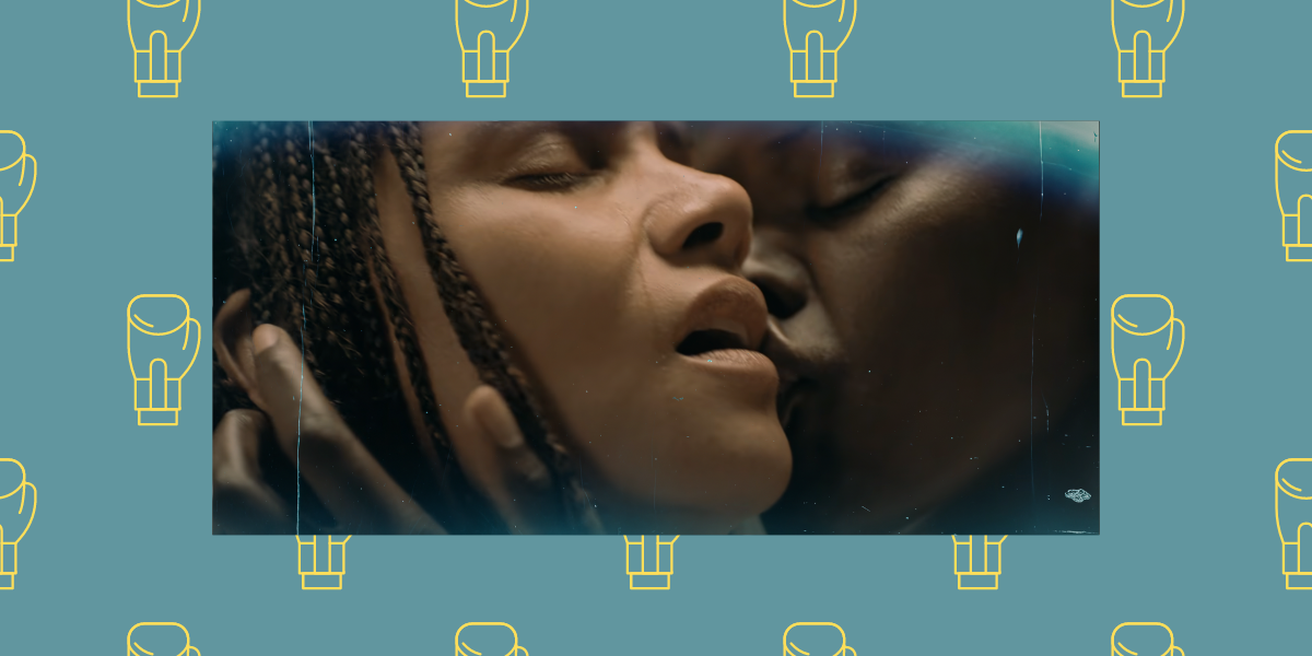 A screenshot of Halle Berry in Bruised has her crying with relief while she is kissed by Sheila Atim. This image is collaged in front of a blue background with boxing gloves on it.