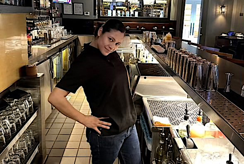 Alexandra Rauda poses with one hand on her hip behind the bar.