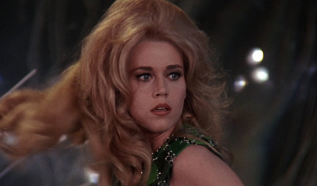 Jane Fonda as Barbarella with big hair looks over her shoulder