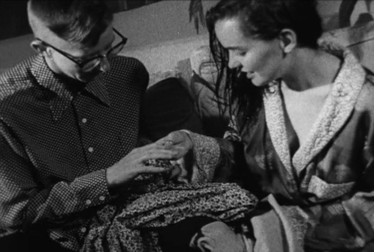 Guinevere Turner in a robe holds V.S. Brodie's hand and looks at her nails.