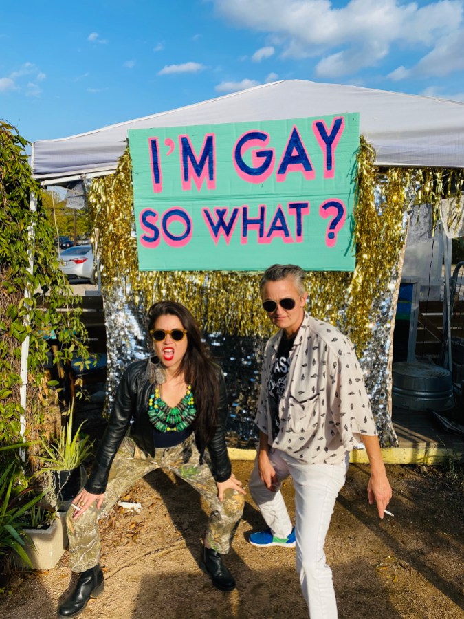 people beneath a sign that says I'M GAY SO WHAT?