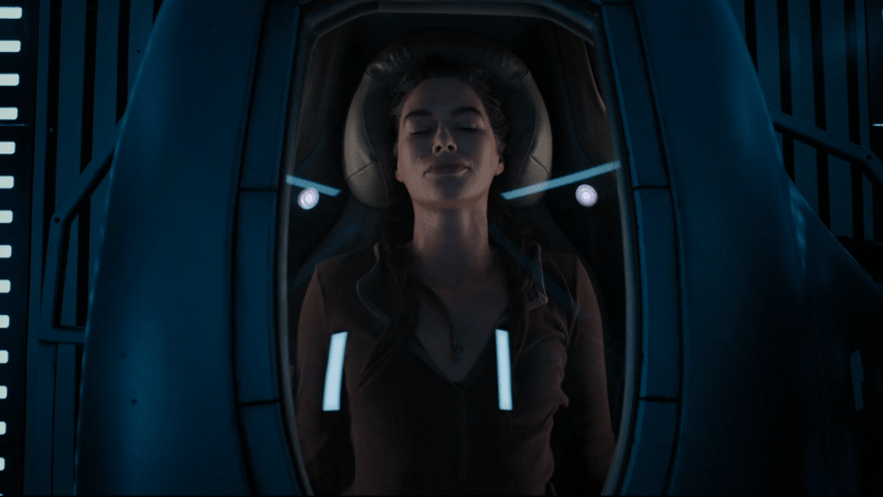 Lena Headey as Aster in a space pod, looking like she is asleep