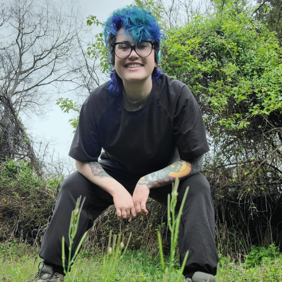 Nico leans down and smiles while modeling the tee shirt and pants