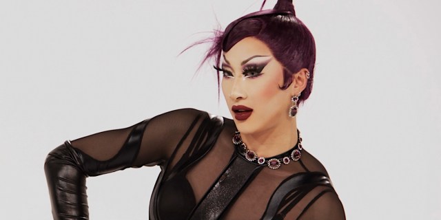 Drag Race 1614: A close up of Nymphia Wind posing in black latex and a dark red lip