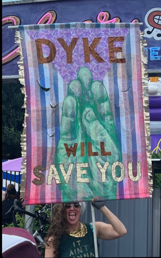 a person holds a sign that says DYKE WILL SAVE YOU