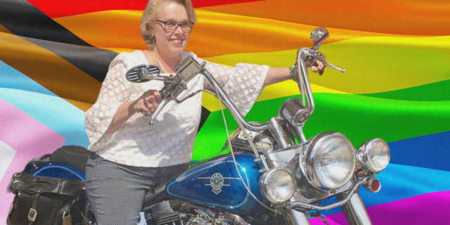 Motti's mom on a motorcycle with a rainbow flag behind her