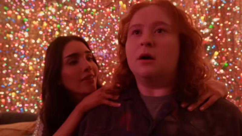 In a room full of rainbow lights, Hannah looks stunned as a girl puts her hands on her shoulders