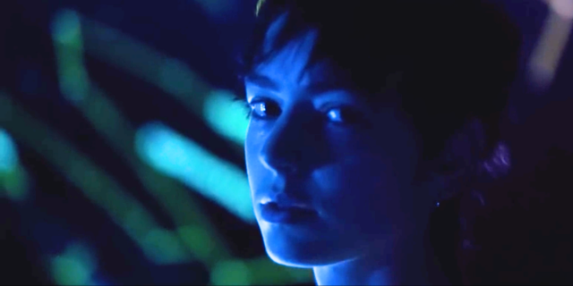 Brigette Lundy-Paine interview: a close up of Brigette looking at the camera wash in blue lighting