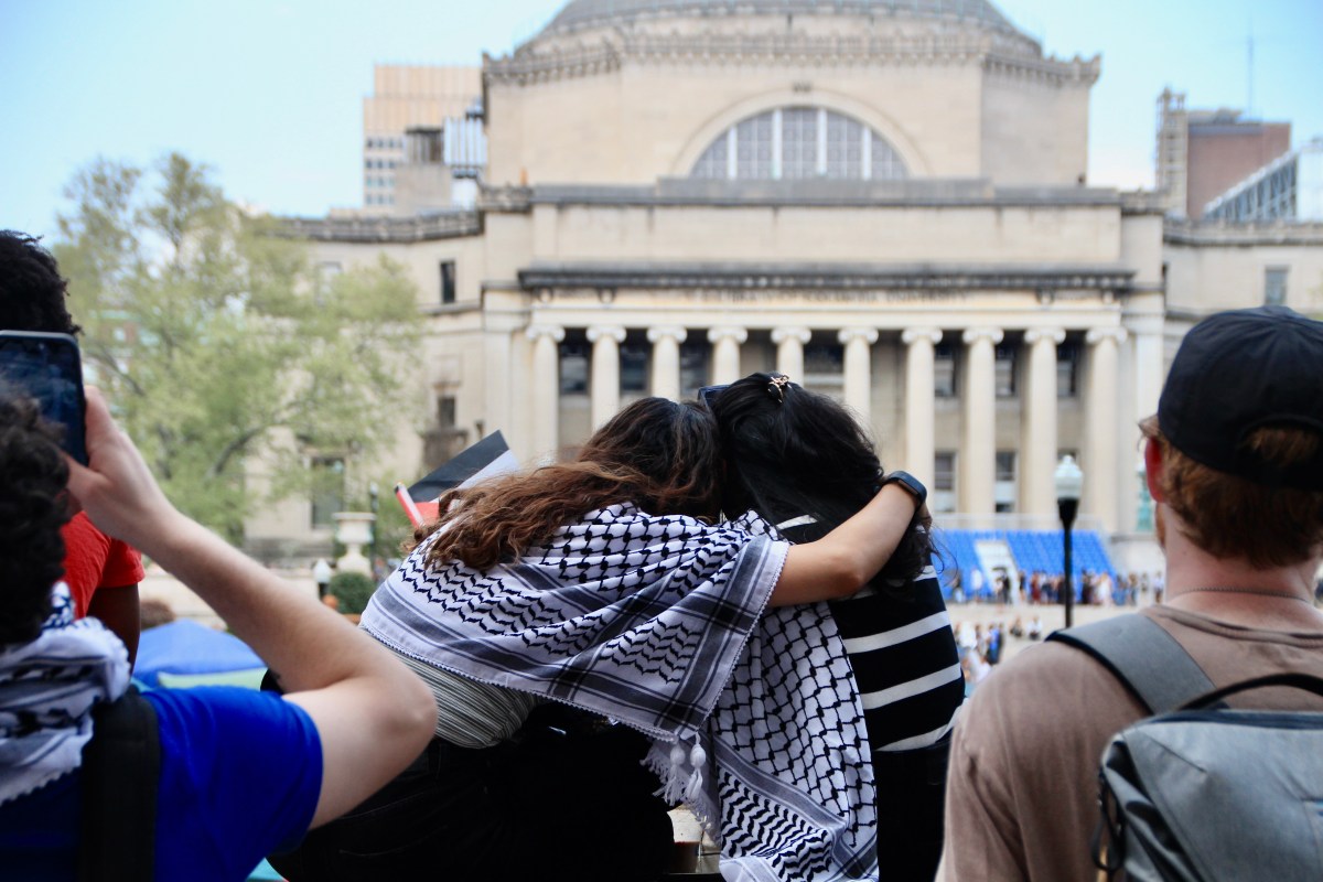 Two students embrace as they sit on a ledge overlooking the encampment. Photo by Mukta Joshi. 