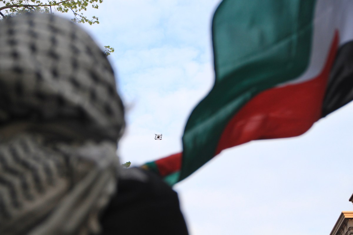 An NYPD drone hovers in the air as a student protestor waves the Palestinian flag. Photo by Mukta Joshi.