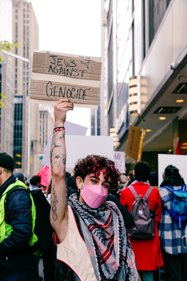 A person holds a sign that says JWES AGAINST GENOCIDE