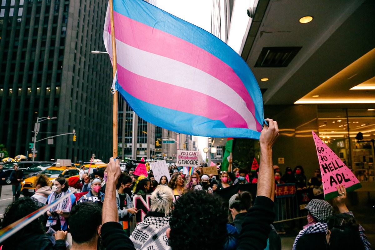 a trans flag waves at the ACT UP NY demonstration outside the GLAAD Awards