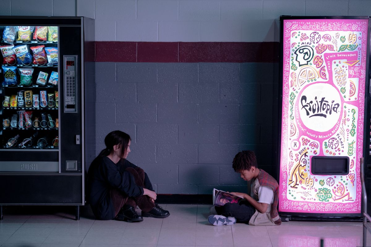 Brigette Lundy Paine sits between two vending machines across from Ian Foreman