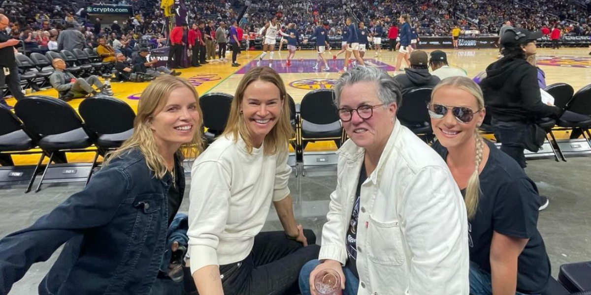 Leisha Hailey and Rosie O'Donnell enjoying a Sparks game, posed smiling with the court behind them.