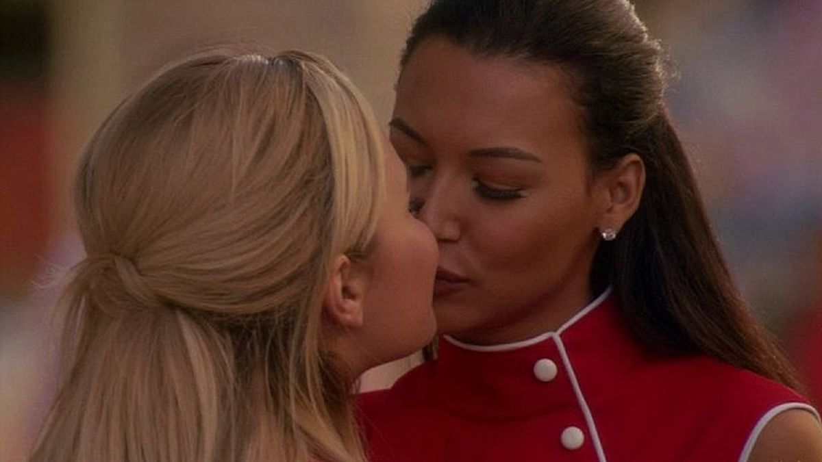 Santana kisses Dani in matching red waitress outfits.
