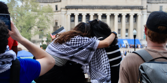 Two students embrace as they sit on a ledge overlooking the encampment. Photo by Mukta Joshi.