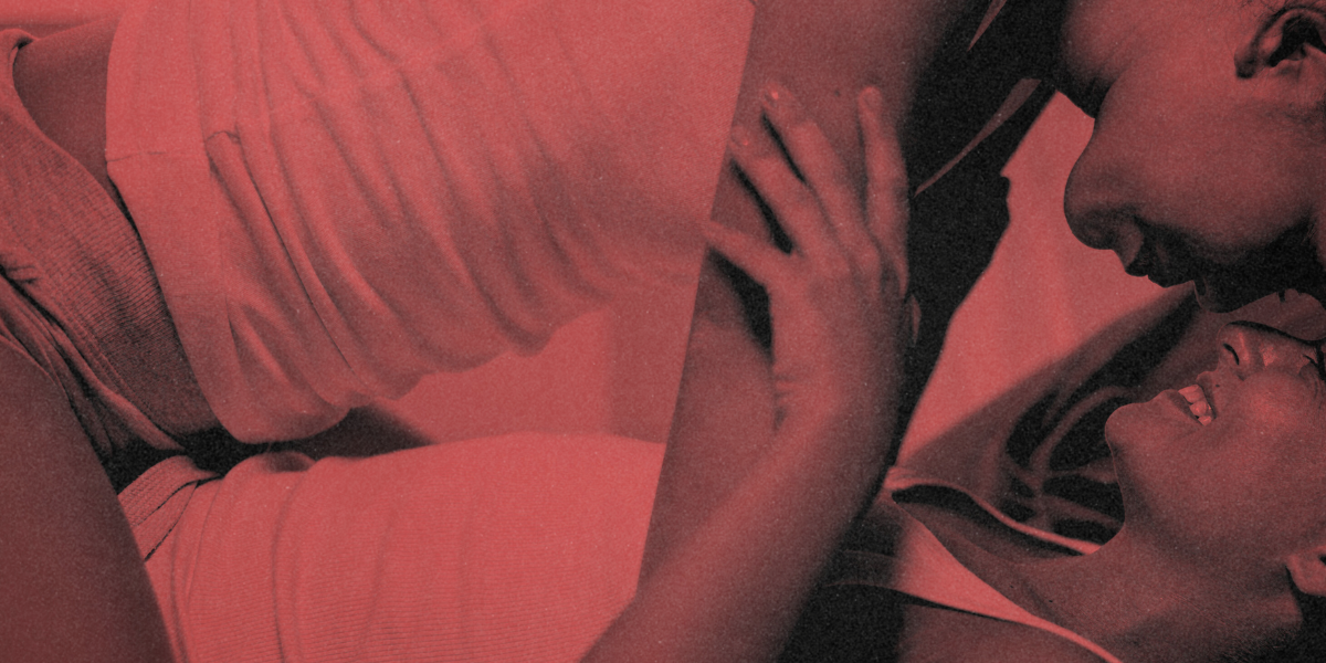 two queer people of color wearing tank tops embrace on a bed, one clearly topping the other, both smiling, the bottom broadly and the top softly. the image is red.