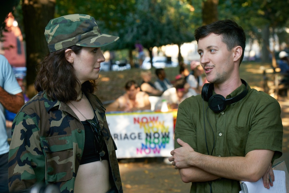 Rhys talks to Dana with his arms crossed, Dana wears army gear