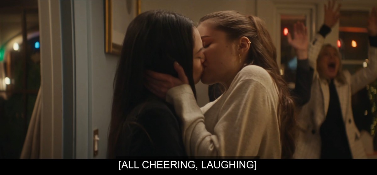 They kiss while everyone cheers and laughs