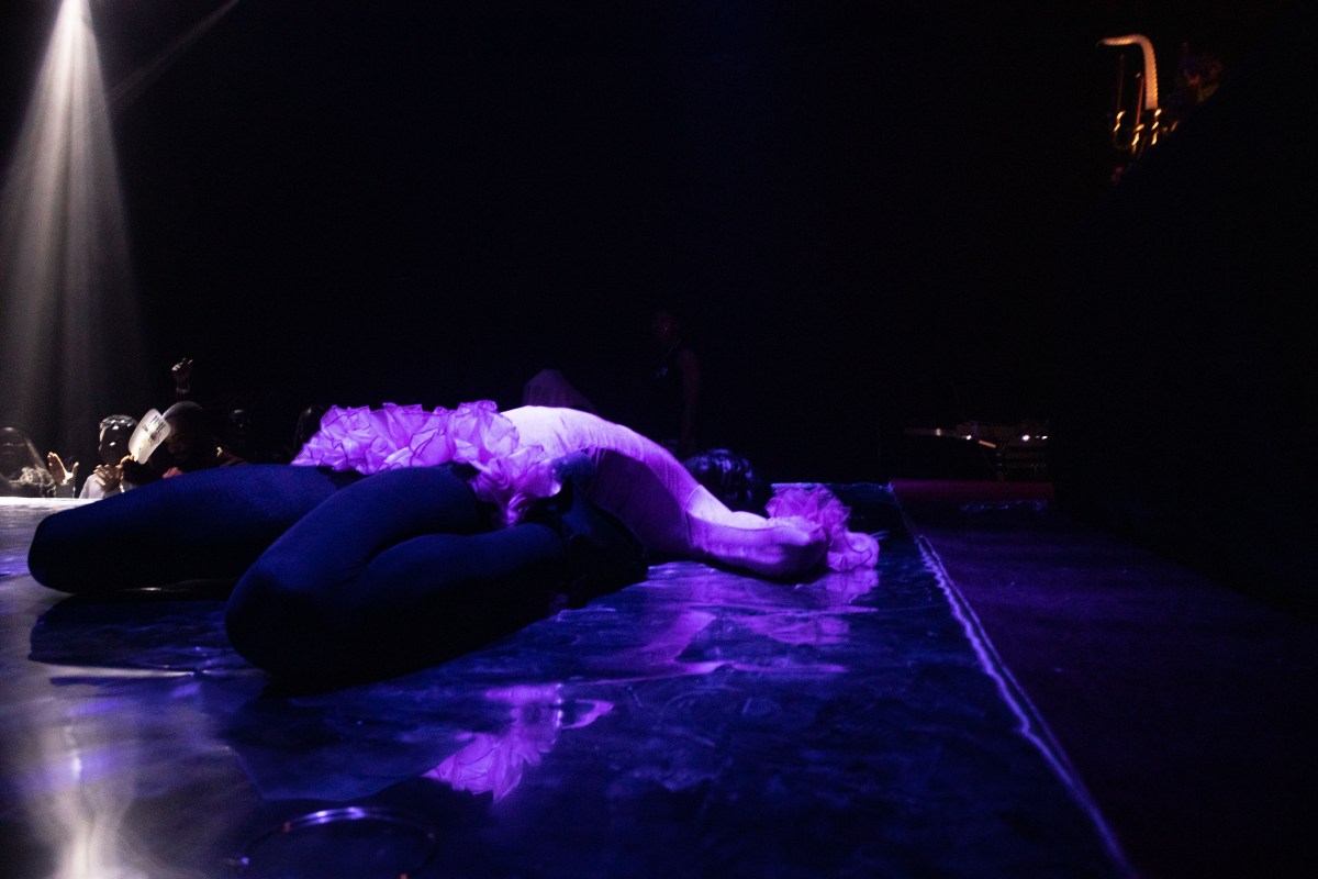 a ballroom performer in a death drop, cast in purple light