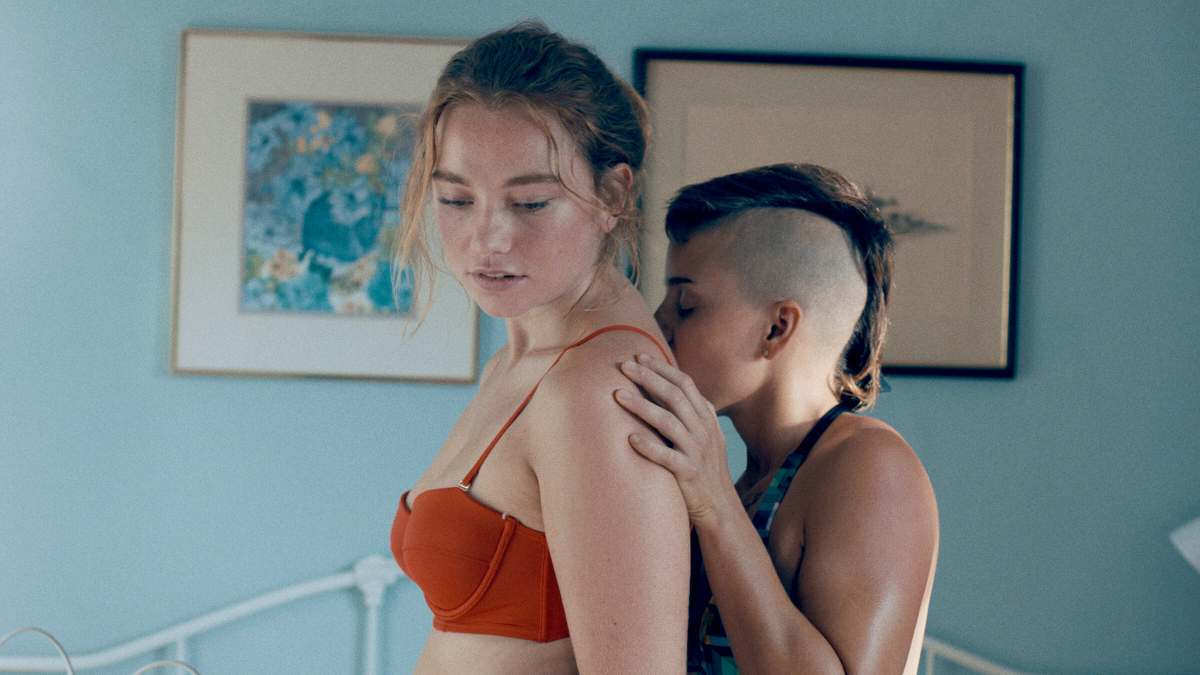 A girl in a bikin top has her back kissed by a nonbinary person in Princess Cyd