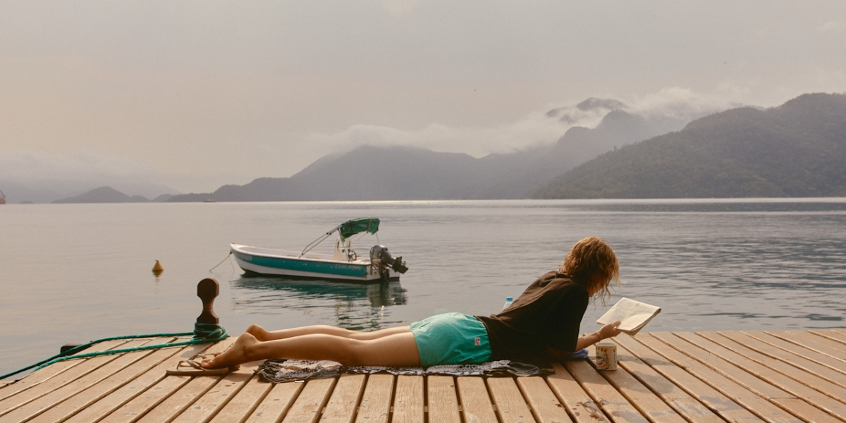 person on lake deck reading