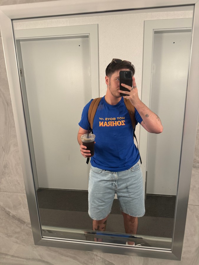 Motti takes a mirror selfie in a hot boys for Zohran shirt