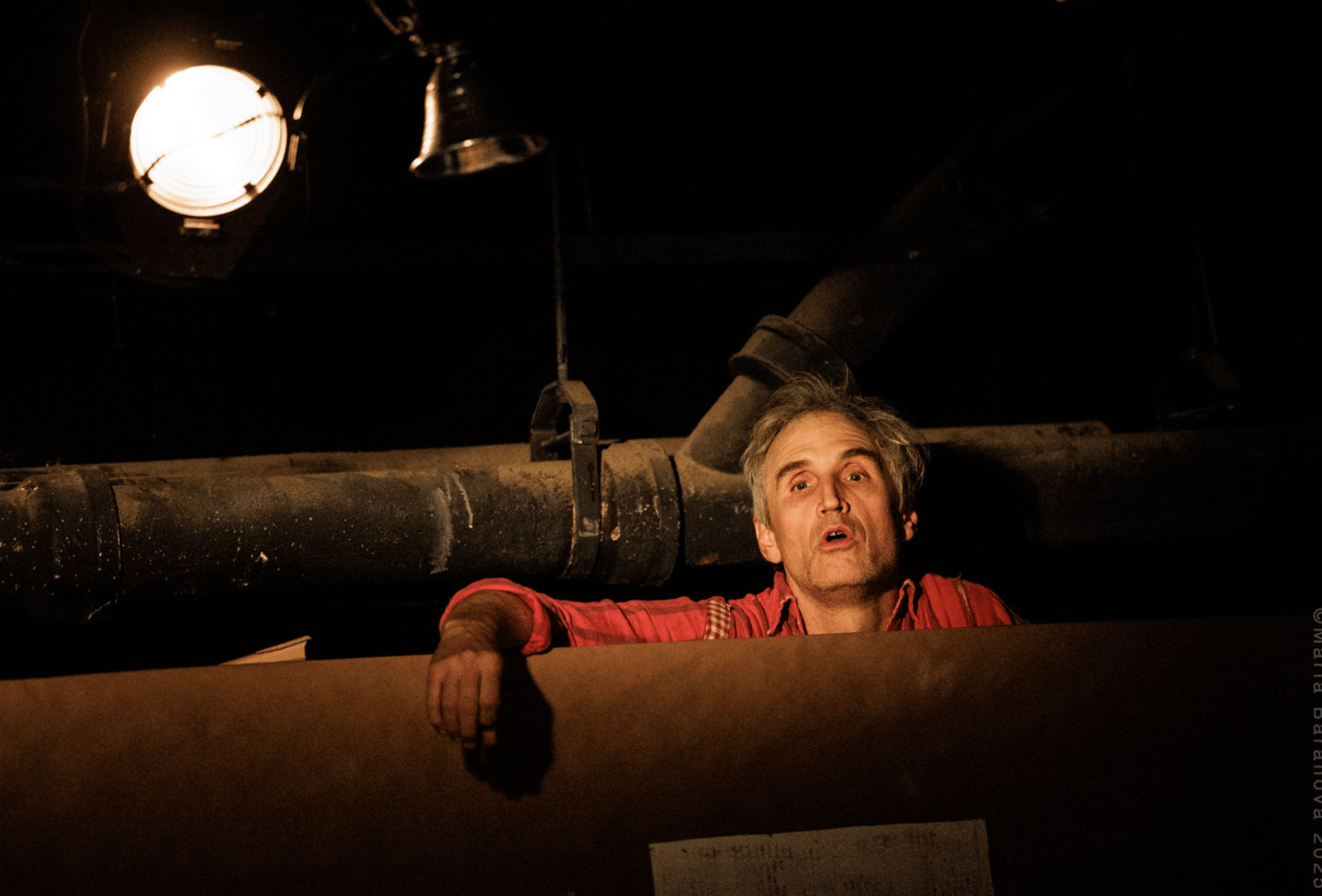 A man pokes his head out between two long pipes.