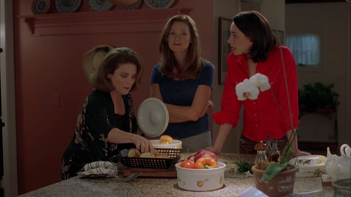 Jennifer Westfeldt stands with her arms crossed next to Heather Juergensen as Tovah Feldshuh serves food.