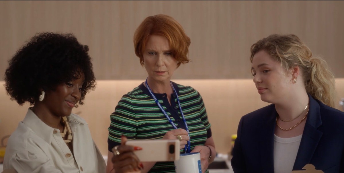 Miranda looking at a phone being held up by two young women
